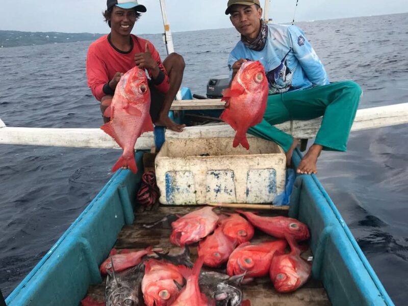 Two local anglers holding red snapper with the day's catch on a Lombok fishing charter